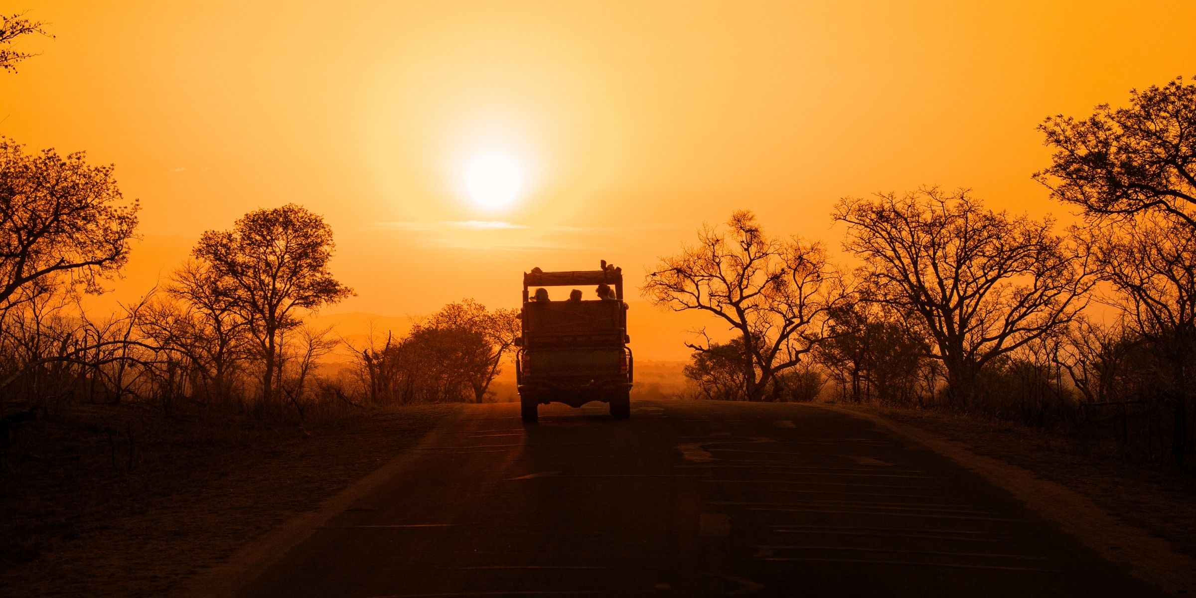 Students and safari vehicle at sunset during a Tanzania school trip.